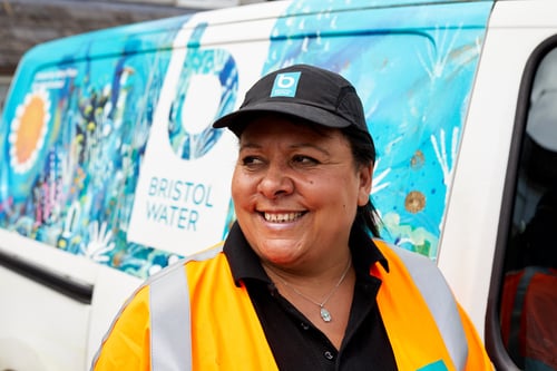 Woman wearing a cap smiling in front of a van