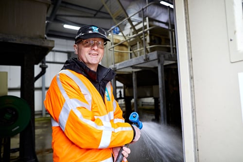 Man spraying a factory floor wearing high vis