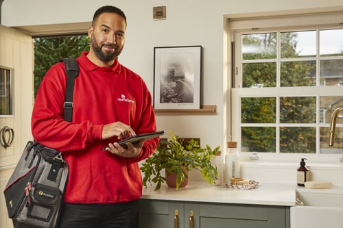 HomeServe engineer in the kitchen of a customers home smiling for the camera
