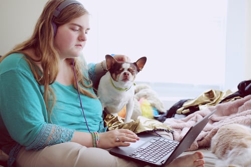 Vulnerable woman with her dog typing on a laptop